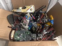 Overall view of cardboard box containing mixed action figures, statues and a shuttle vehicle