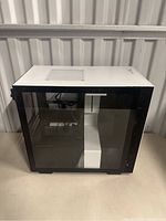 White NZXT computer case visible from the side showing tempered glass panel and ventilation.