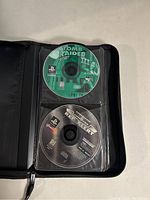 Binder open, showing two discs labeled Tomb Raider III and Command & Conquer Red Alert in plastic sleeves