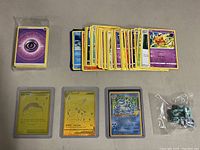 Photo of assorted Pokemon cards including three holographic cards and a small bag of dice