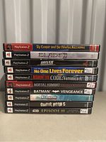 Stack of 10 PlayStation 2 game cases showing fronts and spines with titles and sticker price tags.