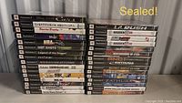 Two stacks of sealed PlayStation 2 game cases