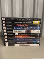 Stack of 10 PlayStation 2 game cases showing titles and some price stickers.