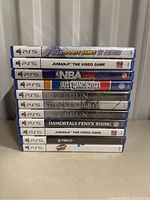 Photo of a stack of 10 sealed PS5 game cases showing titles and condition
