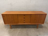 Front view showing overall design, two sliding doors, four drawers, and legs