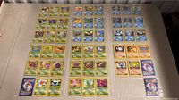 Top-down view of approx 56 Pokemon cards displayed on table