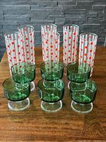 Set of 12 glasses: 6 tall Dominion glasses with bright red polka dots and white frosted vertical stripes, and 6 green Arcoroc sherbet glasses with clear stems.