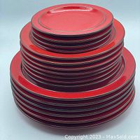 Stacked set of 17 red Thomas Flame plates, showing three size groups stacked in tiers.