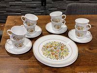 Seven cups stacked two high each on eight saucers with seven dinner plates below, all showing the Indian Summer floral pattern by Corelle.