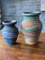 Two Alfadom vases standing on wood surface showing relative size and glaze colors.