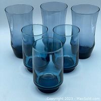 Front view group photo of six blue glasses: three taller gradient blue Libbey Appollo Blue glasses and three shorter footed Dominion glasses.