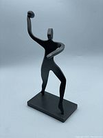 Front angle showing stylized football player statue in throwing pose with left arm extended and right arm cocked holding a football.