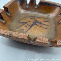 Close-up photo showing the textured rough exterior and glazed interior pattern with maker's mark.