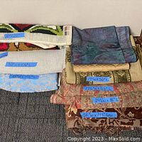 Overview photo of stacked upholstery fabrics showing blue tape measurements on each piece, different colors and patterns visible