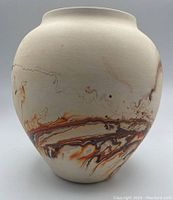Front view showing vase shape and orange-brown marbled patterns on off-white bisque clay.