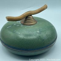 Top angle of lidded pottery dish showing green-blue glaze and driftwood handle on lid.
