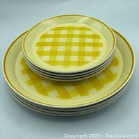 Stack of four smaller plates on top of four larger plates showing checkered yellow pattern and size difference