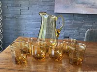 Amber glass pitcher with six matching glasses arranged on a table