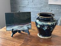Overview of both pottery items on wooden table, vase and decorative plate on black stand