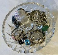 Top view of the crystal ring holder holding 10 assorted ladies rings showing colorful stones and detailed silver-tone settings.