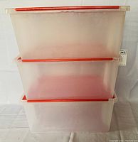 Three stacked semi-transparent plastic totes with red flip lids shown from side.