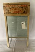 Full view of entire antique washboard showing glass surface and wooden frame with label.