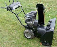 Side view of snow blower showing engine, handles, intake housing