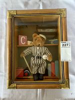 Front view of the wooden glass shadow box containing the bear figurine dressed in vintage baseball attire, standing in front of miniature books and blocks.