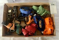 Box with multiple ratchet straps in various colors and metal ratchet mechanisms neatly arranged.