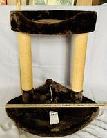 Front view of two-tier cat home with plush carpet, two sisal scratch posts, raised upper sleeping bed, and bendable ball toy at center base.