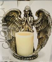 Close-up image of the antique gold angel figurine holding an ivory flameless LED candle showing detailed wings and facial features.