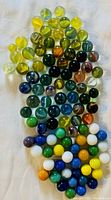 Top view of vintage marbles showing yellow, green, blue, white, orange, and other multicolor patterns arranged on white background.