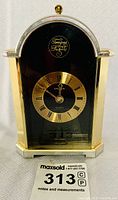 Front view of black and gold Tempus Fugit mantle clock with arched top and gold Roman numeral dial, showing overall condition and details.