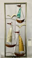 Metal wall art showing three stylized sailing boats with textured and colored sails, two seagulls in cream color, all mounted on a rectangular metal frame with a natural finish.