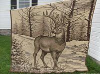 Full view of plush blanket showing large eight-point buck deer in winter forest scene, primarily beige and brown tones.
