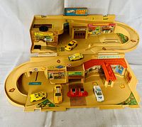 Overview of Hot Wheels Sto N Go Service Center playset with 5 toy cars arranged on it.
