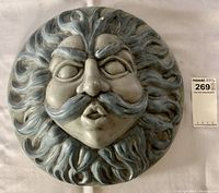 Front view of the ceramic stoneware North Wind outdoor wall plaque showing detailed facial features and textured flowing hair design in blue-gray glaze.