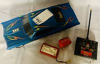 Blue remote control Chevy Impala car with flame decals, next to remote, battery pack, and charger on a white background.