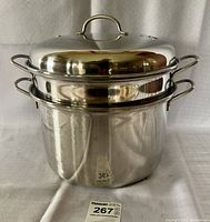 Full assembled view of the multi cooker with colander inserts and lid stacked on top showing size and finish.