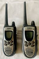 Front view of the two Uniden walkie talkies showing screen displays, buttons and speaker grill.
