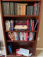 Books on top three shelves of wooden bookcase showing antique hardcover books and various newer books with titles visible including 'Body' and 'The Human Body'