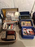 Seven plastic tubs filled with assorted books, including some with Harvard Classics and classic literature.