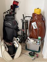 Overview of lot showing two golf bags, pull carts, golf balls bin, bowling ball and accessories