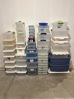 Overview showing five vertical stacks of assorted clear plastic tubs against wall