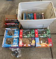Overview of entire lot showing 8 McFarland sports figures in various original boxes and a large plastic storage tub.