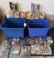 Two blue plastic tubs with 23 McFarland sports figures displayed in original packaging showing various sports and teams.