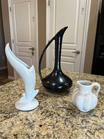 Photo showing all three pieces together on a granite counter: black ewer, white flower vase, white pitcher.