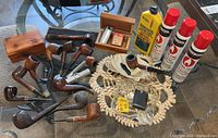 Overview of 12 vintage pipes displayed on a table with 3 cans Ronsonol Butane Fuel, Bentley Pipe Lite refill box, metal pipe lighter, 2 ashtrays, and beaded necklace.