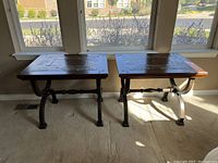 Photo showing two side tables with wooden embossed tops and black metal legs placed on carpet by window.