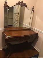 Antique wooden console table with attached mirror, showing carved details and metal drawer pulls.